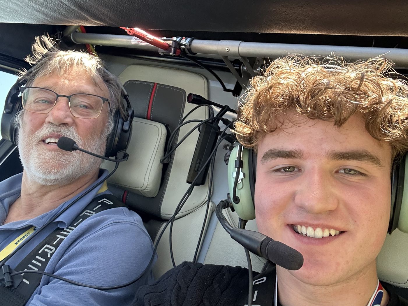 Nathaniel and a pilot in headsets in the cockpit of a small aircraft.