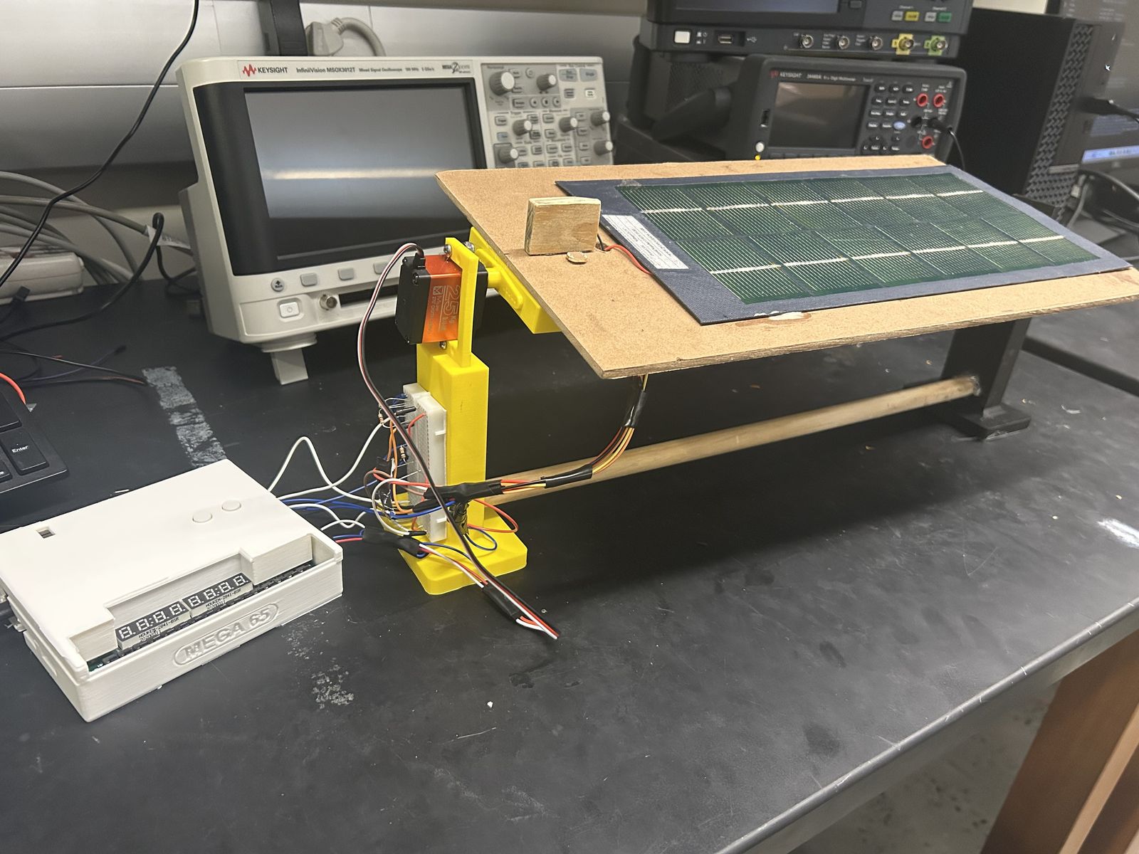 The solar tracker on a lab bench: a panel on a servo-driven 3D-printed mount, wired to a breadboard and an FPGA development board.